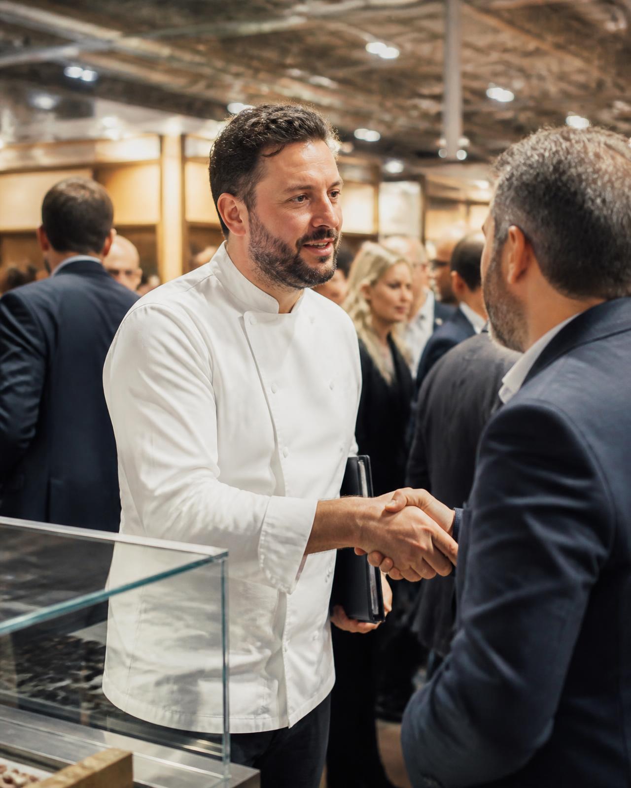 Uno chef stringe la mano a un distributore nel padiglione di una fiera