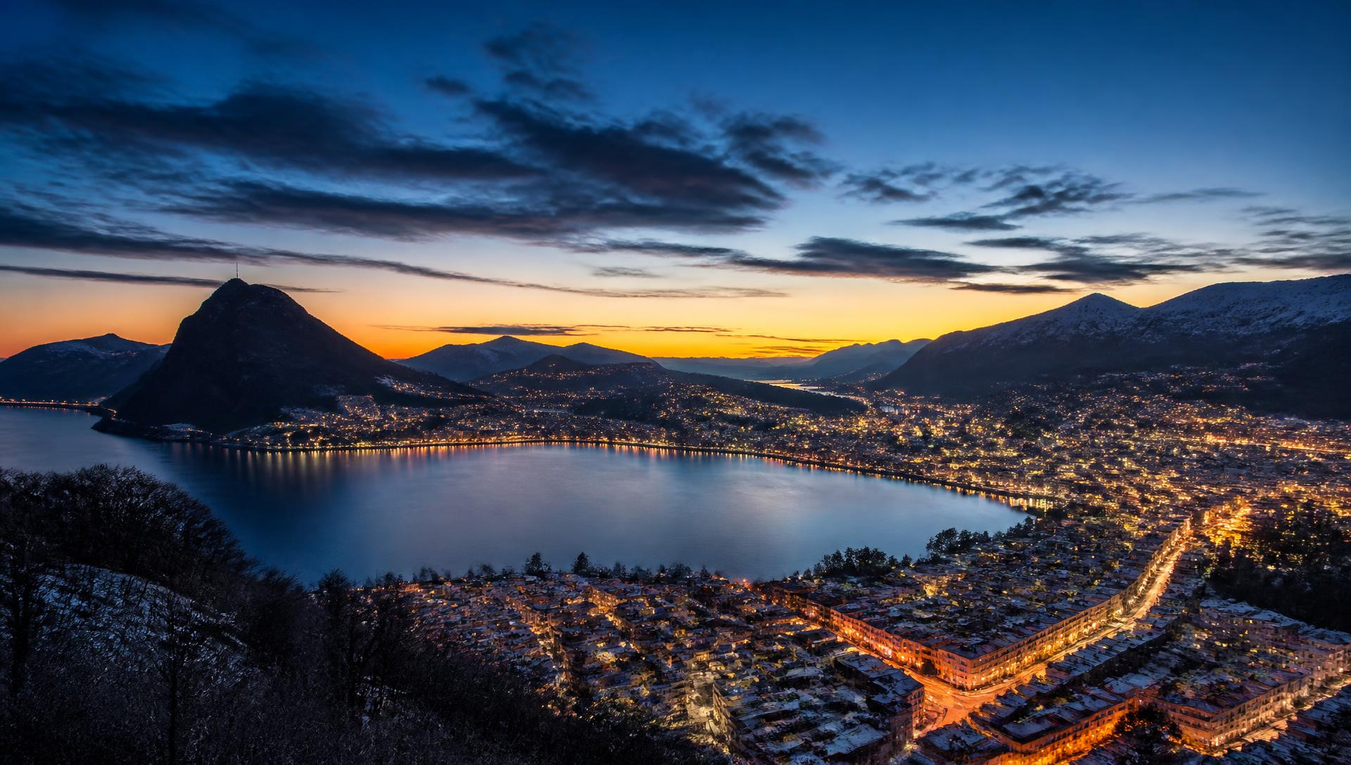 Vista panoramica di Lugano al tramonto con il lago e le montagne